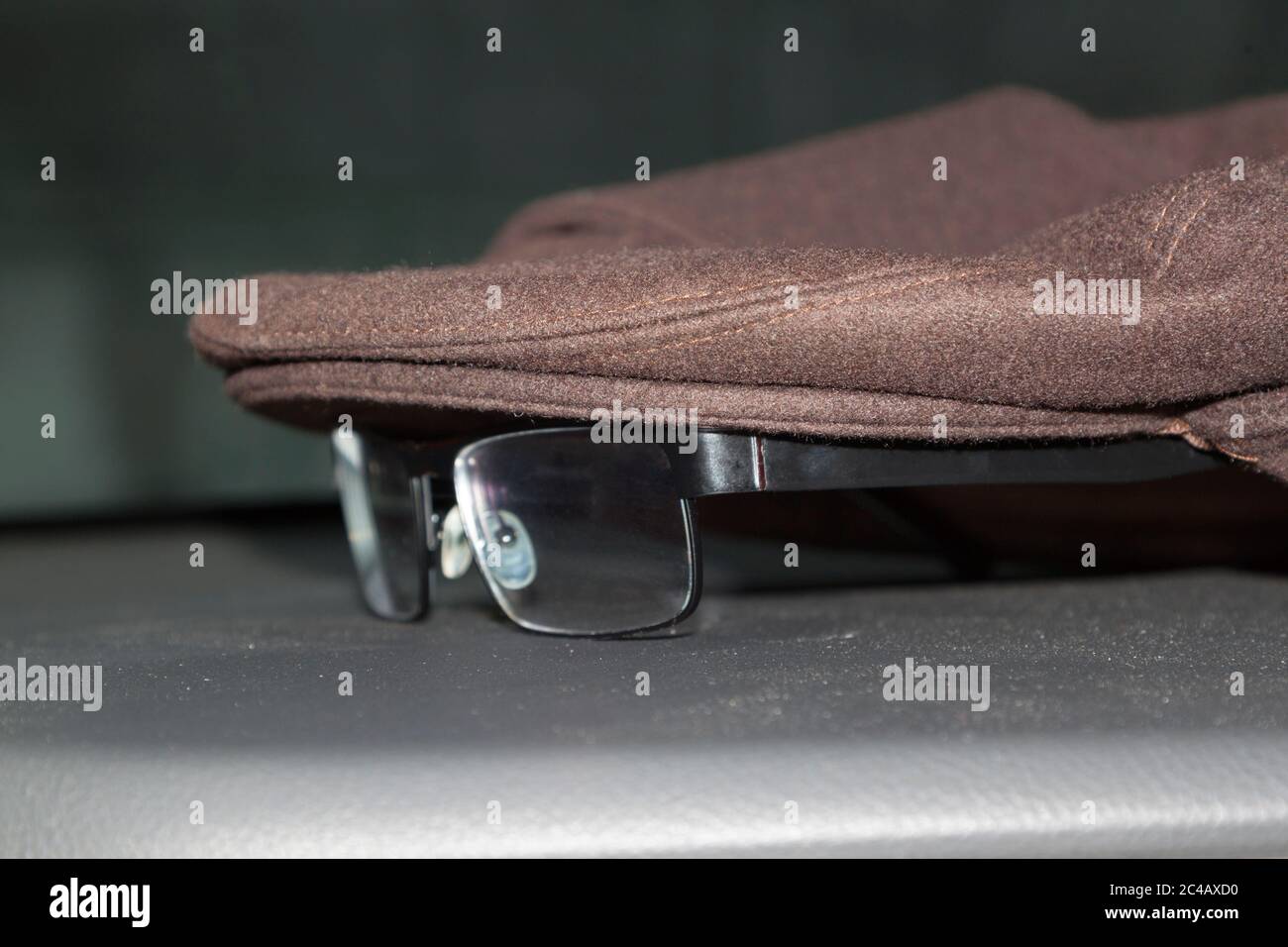 Berretto inglese e bicchieri neri. Primo piano su sfondo scuro. Foto Stock