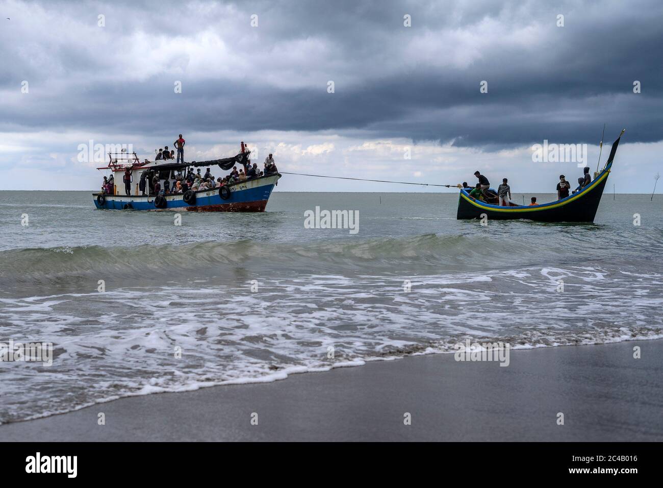 Nord Aceh, Aceh, Indonesia. 25 Giugno 2020. Il pescatore di Acehnese tira la barca di Rohingya verso la spiaggia di Lancok nel nord di Aceh, provincia di Aceh. Decine di Rohingya sono stati salvati in mare dai pescatori indonesiani mentre si è imbarcati su una barca rotta nelle acque al largo della provincia più settentrionale di Aceh, hanno detto i funzionari. Credit: Zikri Maulana/ZUMA Wire/Alamy Live News Foto Stock