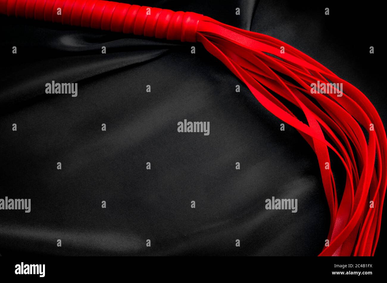 Kink sessuale e giochi erotici concetto con un blogger rosso BDSM intorno alla seta nera con spazio di copia Foto Stock
