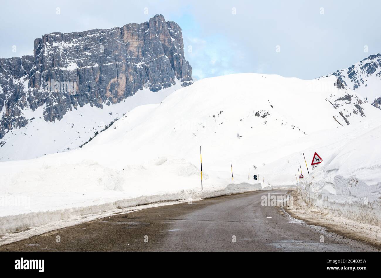 Strada deserta passo di montagna nelle Alpi europee in inverno. Sullo sfondo è visibile un'imponente vetta rocciosa. Foto Stock