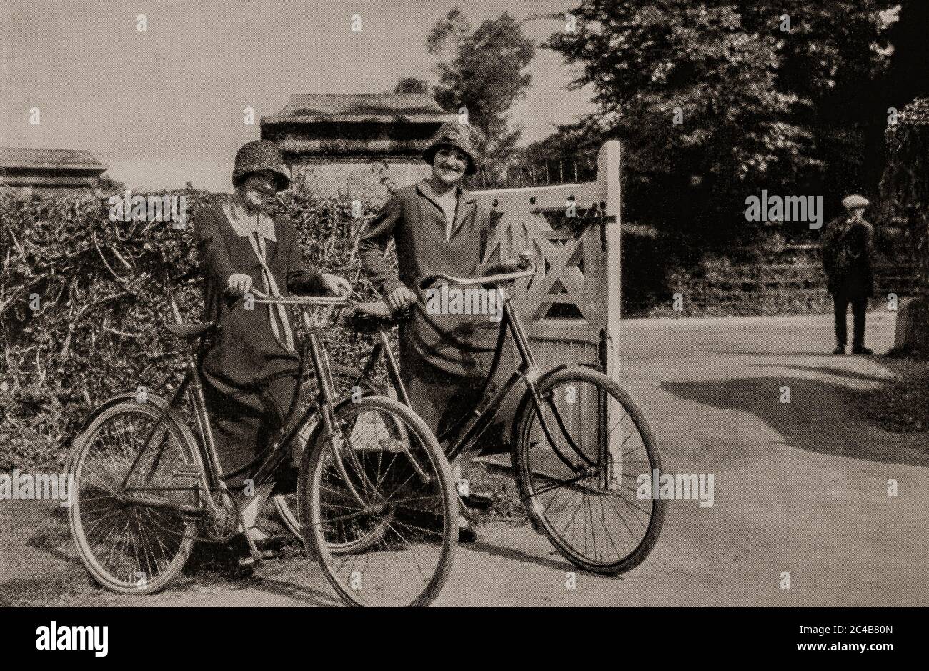 Una scena di due giovani Signore all'inizio degli anni '20 in bicicletta vicino a Killarney, ora parte del Killarney National Park nella contea di Kerry. Originariamente fotografato da Clifton Adams (1890-1934) per 'Ireland: The Rock Whence i was hewn', una rivista nazionale di geografia dal marzo 1927. Foto Stock