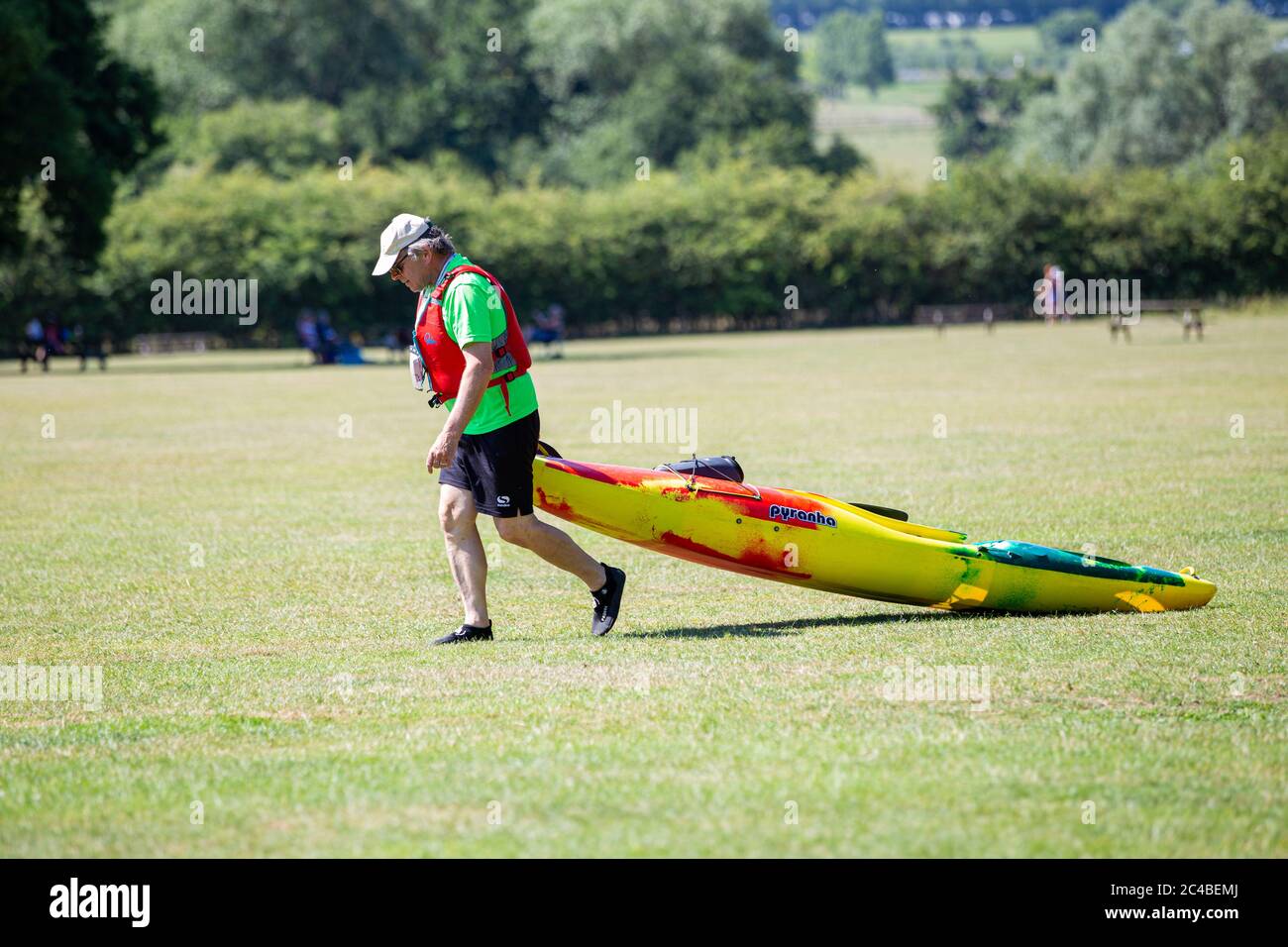 25 Giugno 202020Parque Paese di Teston Bridge. Il giorno più caldo dell'anno finora. Un uomo tira una canoa attraverso l'erba fino al fiume Medway. Foto Stock