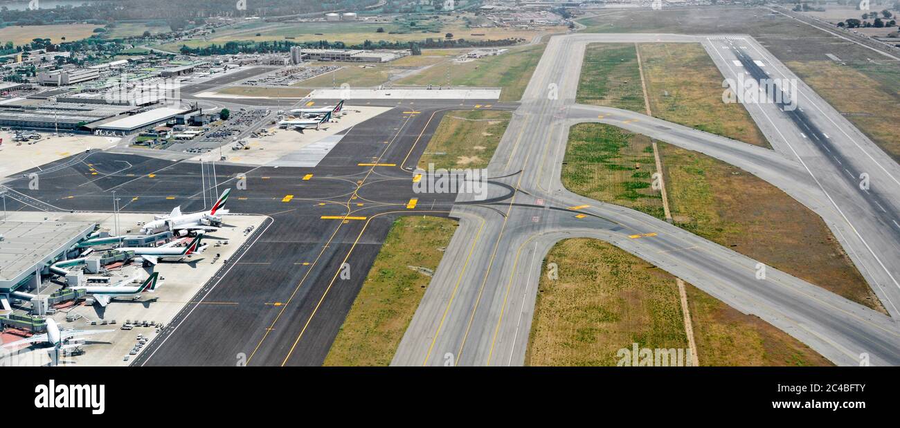 Vista aerea delle piste di atterraggio e di tassaggio agli edifici del terminal visti da un aereo jet decollo dall'Aeroporto Internazionale di Roma Fiumicino Italia Foto Stock