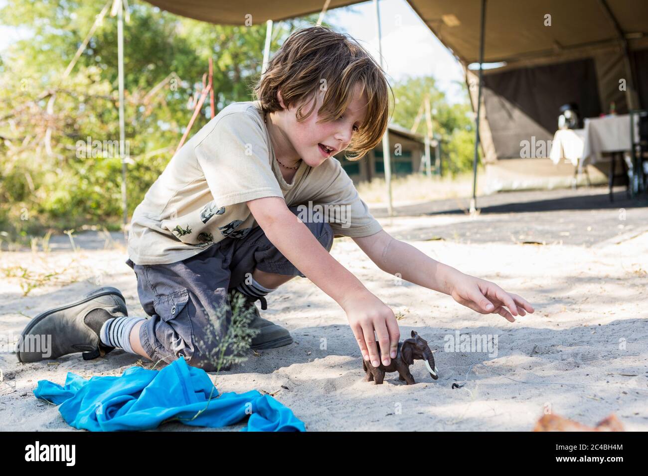 Un ragazzo di sei anni che gioca con i giocattoli in un campo teso, Nxai Pa, Botswana Foto Stock