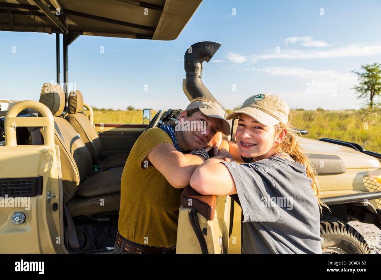 Madre e figlia adolescente appoggiati su un veicolo da safari, Botswana Foto Stock