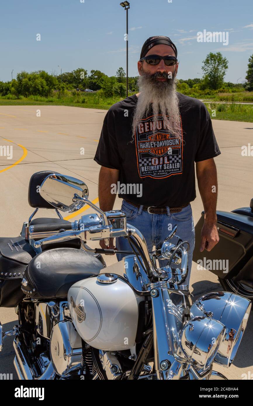 Un uomo con la bearded si trova accanto alla sua moto Harley Davidson a Marion, Indiana, USA. Foto Stock