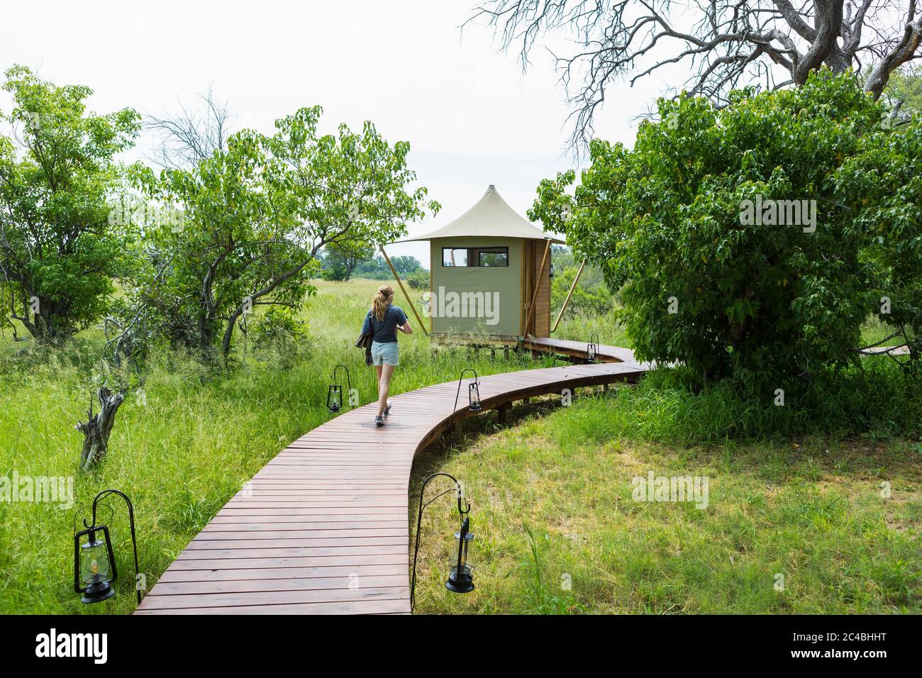 13 anni ragazza che cammina sentiero in legno, campo tenda, Botswana Foto Stock