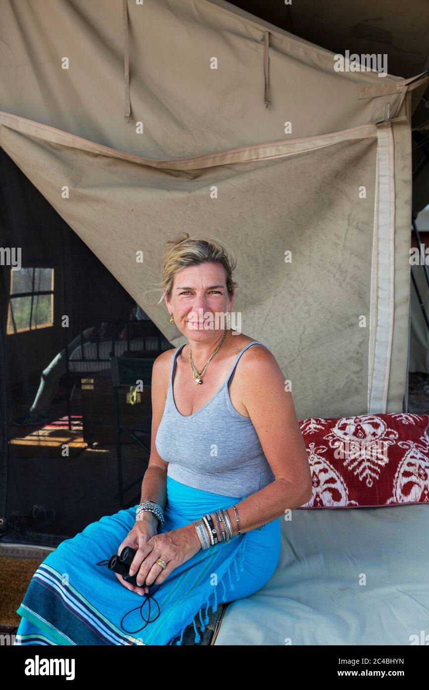 Una donna seduta su un letto in una tenda in un campo riserva naturale. Foto Stock