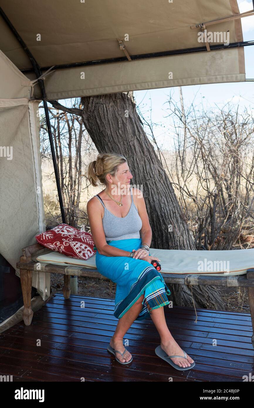 Donna matura seduta sotto tela, da una tenda in un campo riserva naturale. Foto Stock