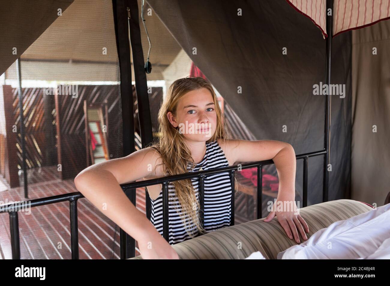 Una ragazza di dodici anni accanto a un letto in una tenda. Foto Stock