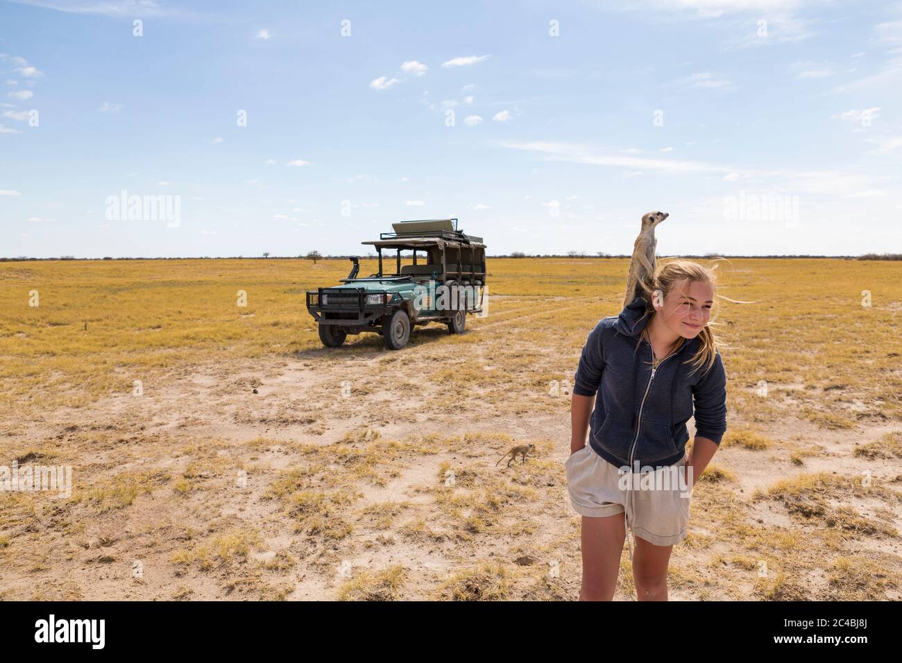 Ragazza di 12 anni con Meerkat sulla testa, deserto di Kalahari Foto Stock