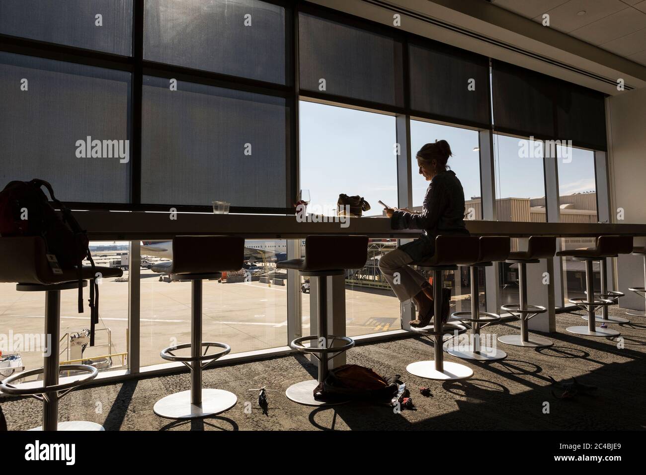 Una donna matura, una donna dirigente seduto utilizzando un computer portatile in una sala partenze aeroporto Foto Stock