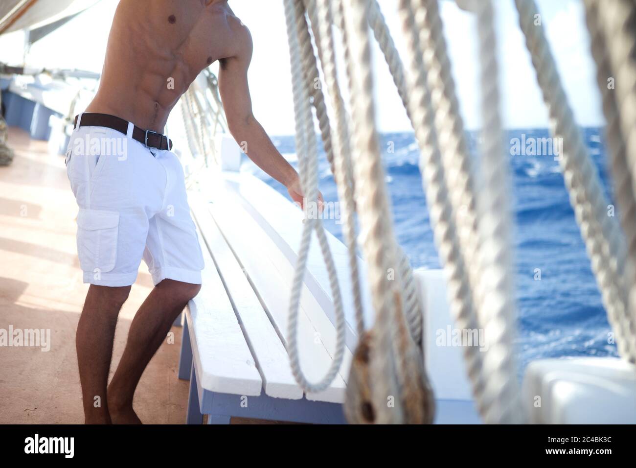 Uomo senza senso che indossa pantaloncini bianchi sul ponte di una barca a  vela, rigging Foto stock - Alamy