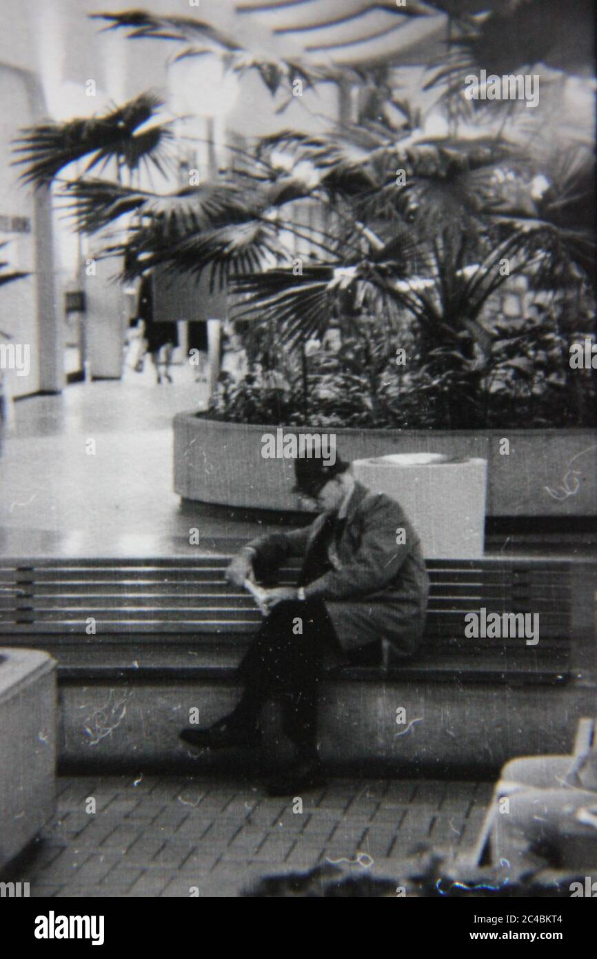 Bella fotografia in bianco e nero degli anni '70 di un vecchio che legge un libro al centro commerciale locale. Foto Stock