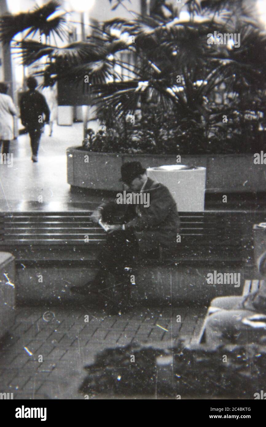 Bella fotografia in bianco e nero degli anni '70 di un vecchio che legge un libro al centro commerciale locale. Foto Stock