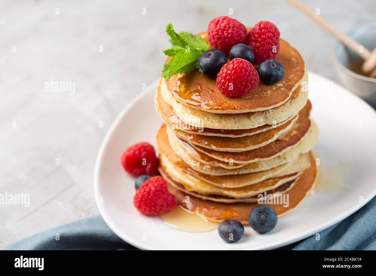 Pancake con mirtilli, lamponi, menta e miele per colazione Foto Stock