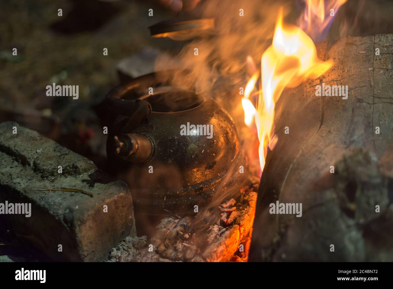 Il bollitore viene riscaldato su un fuoco acceso di notte all'aperto Foto Stock