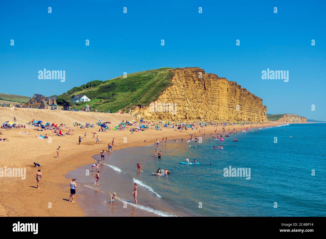 West Bay Beach Dorset, Regno Unito. Mare con persone che si godono il tempo estivo in spiaggia e remando in mare. Foto Stock