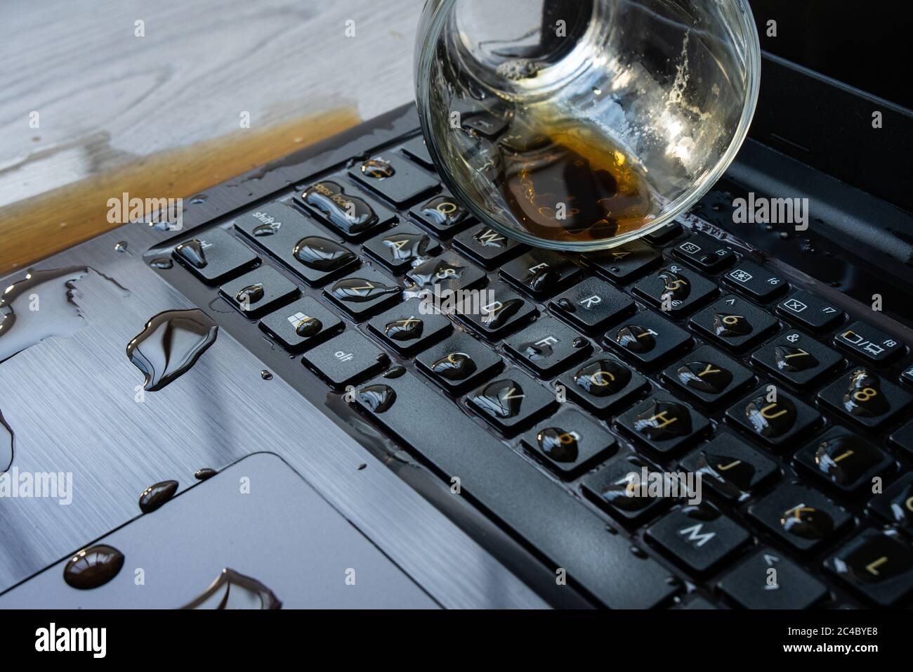 Il caffè viene versato accidentalmente sul computer portatile. La tastiera è piena di liquidi e il computer è rovinato. Foto Stock