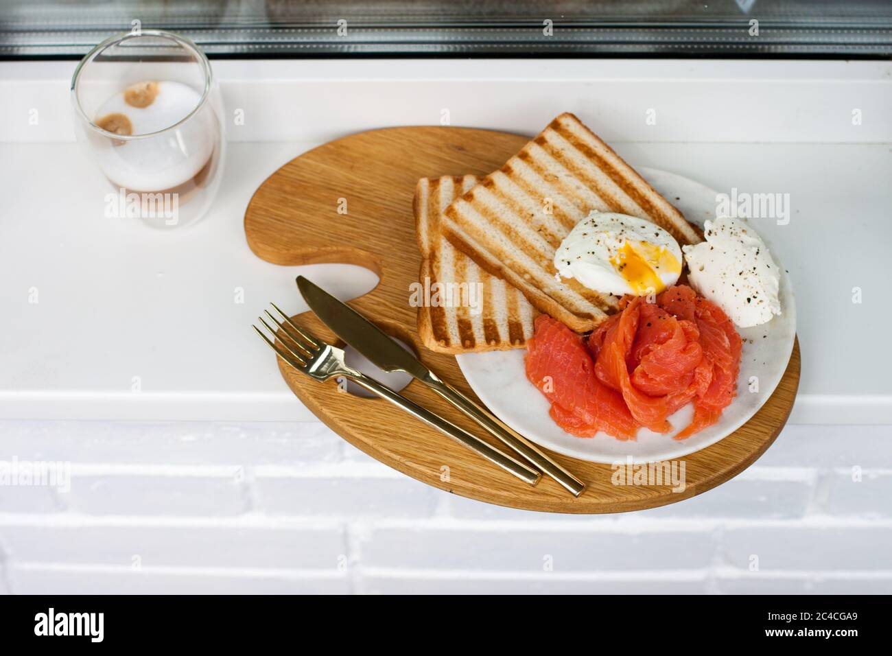 Menu colazione: Pane tostato, salmone affumicato, uova in camicia e tazza di caffè sul davanzale bianco Foto Stock