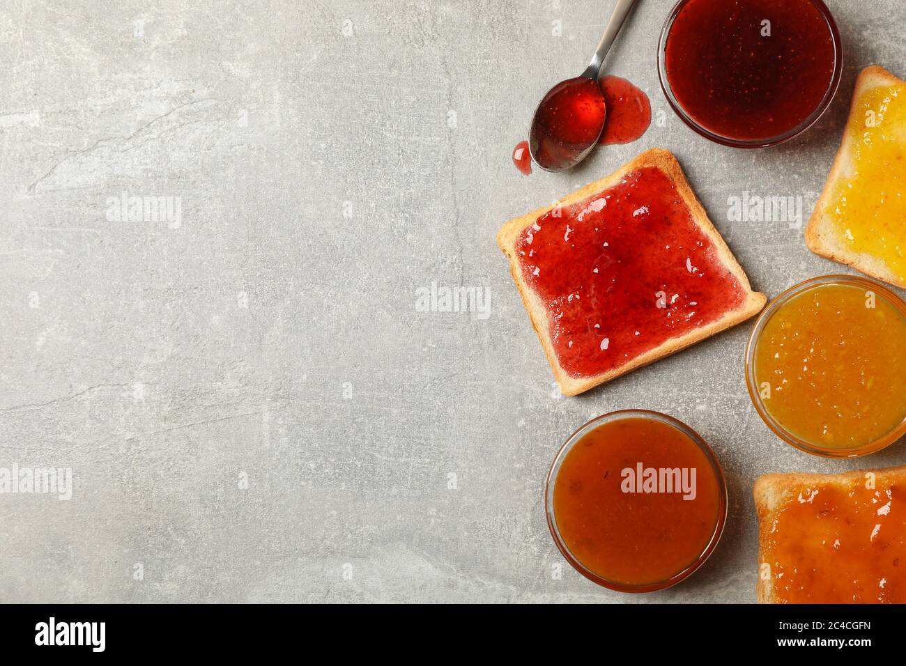 Ciotole e toast con marmellata su sfondo grigio, vista dall'alto Foto Stock