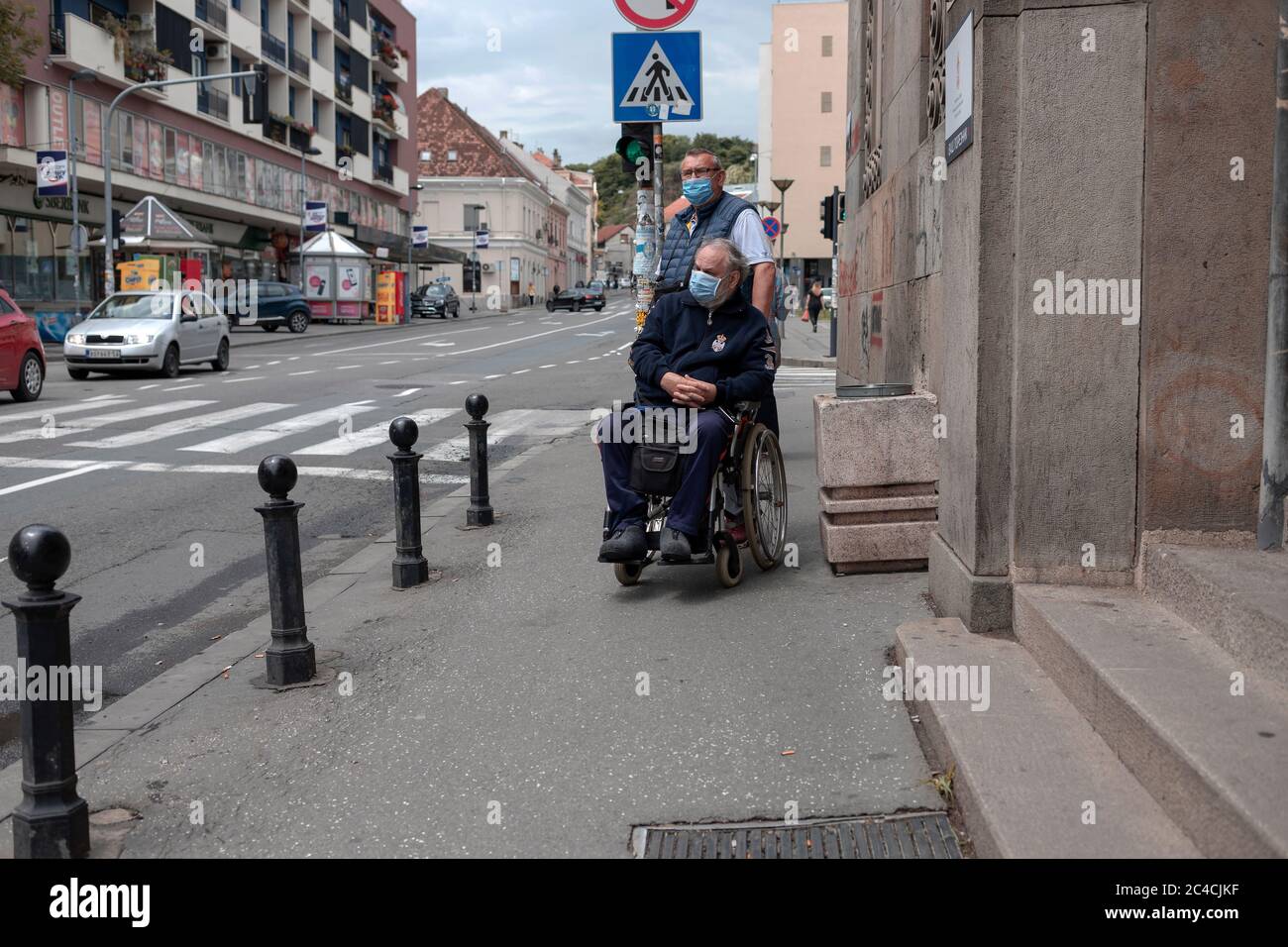 Belgrado, Serbia 18 giugno 2020: Un uomo in sedia a rotelle e il suo compagno in attesa di attraversare la strada Foto Stock