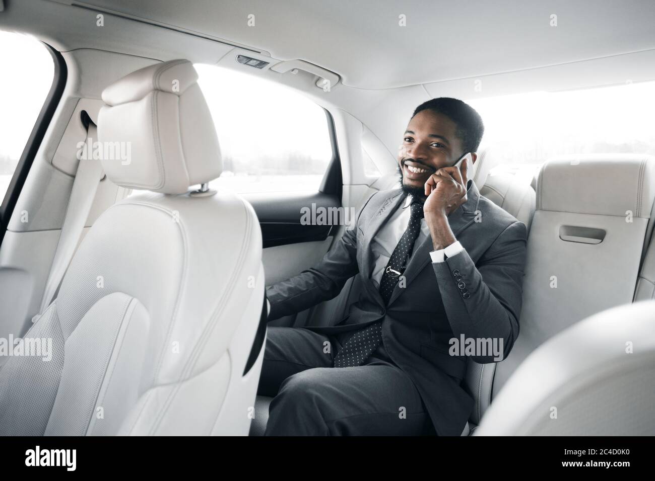 Uomo d'affari che parla al telefono seduto in auto durante il viaggio d'affari Foto Stock