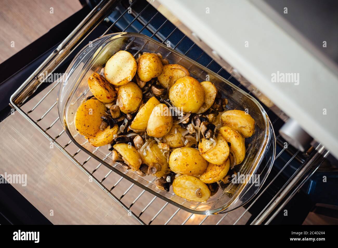 Patate giovani arrostite in teglia di vetro con funghi che prendono dal  forno. Vista angolare Foto stock - Alamy