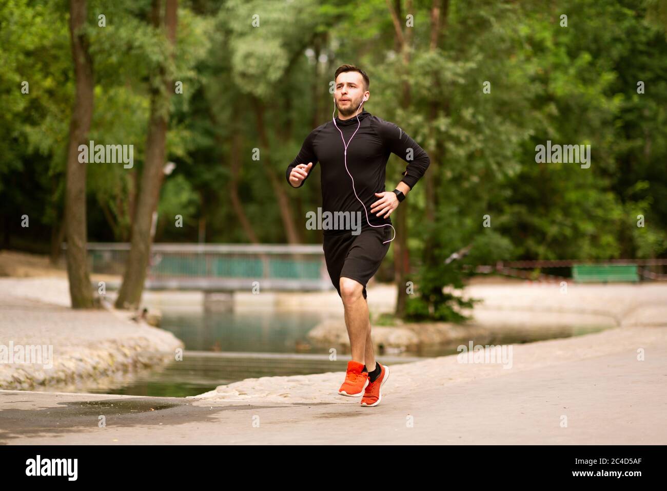 Ritratto di un ragazzo che si occupa di jogging che corre nel parco Foto Stock