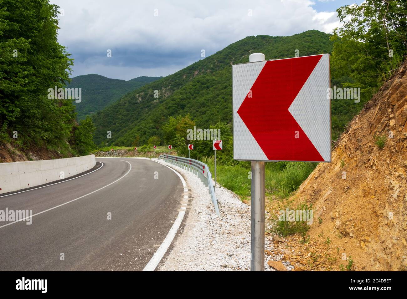 Segnali di una pericolosa svolta su strada di montagna Foto Stock