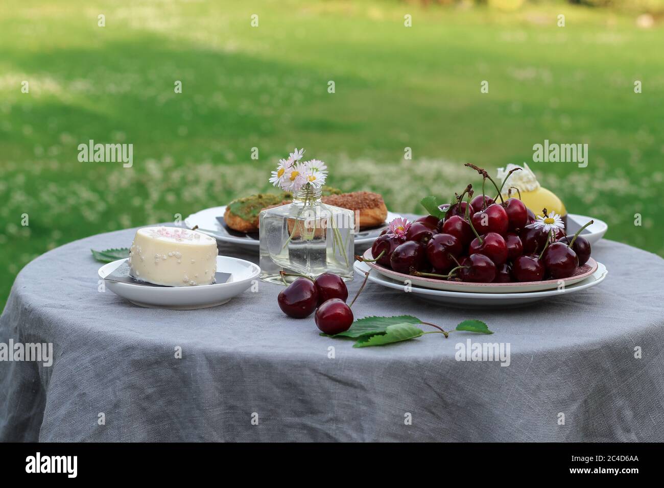 Tavolo da dessert in giardino con ciotola di ciliegie dolci e dessert alla crema Foto Stock