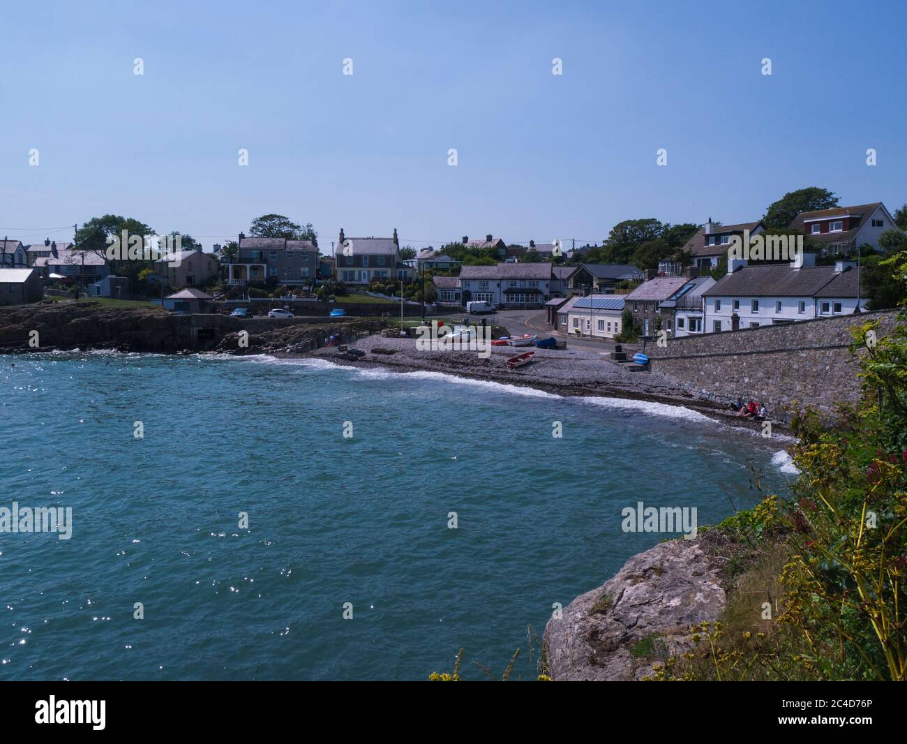 Vista dalla baia alla spiaggia di ciottoli di questo piccolo e popolare villaggio di pescatori Moelfre Isola di Anglesey Galles del Nord Regno Unito con alta marea Foto Stock