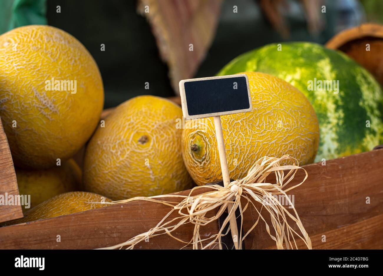 Esposizione di meloni coltivati localmente per la vendita al mercato agricolo locale con cartello scritto a mano in gesso Foto Stock