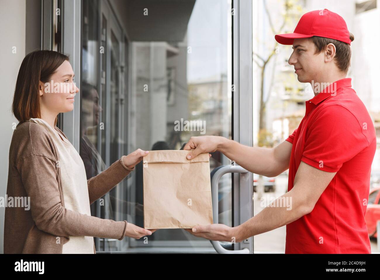 Servizio di consegna moderno a casa. Corriere e cliente si trattengono sul pacco Foto Stock