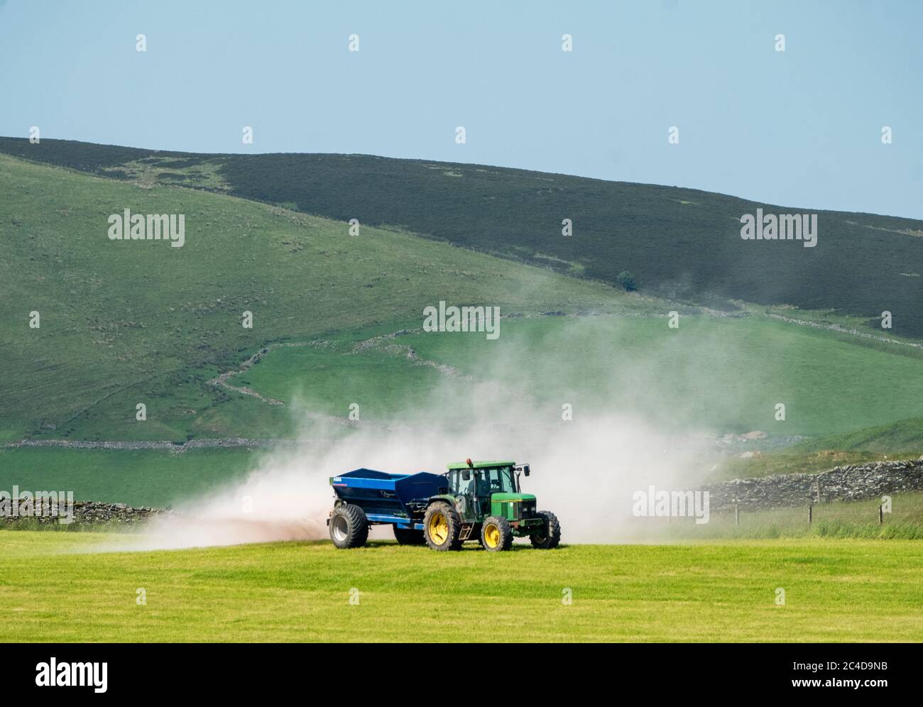 Trattore e rimorchio che sparge calce su un campo di erba vicino a Shankend, Hawick, confini scozzesi. Foto Stock