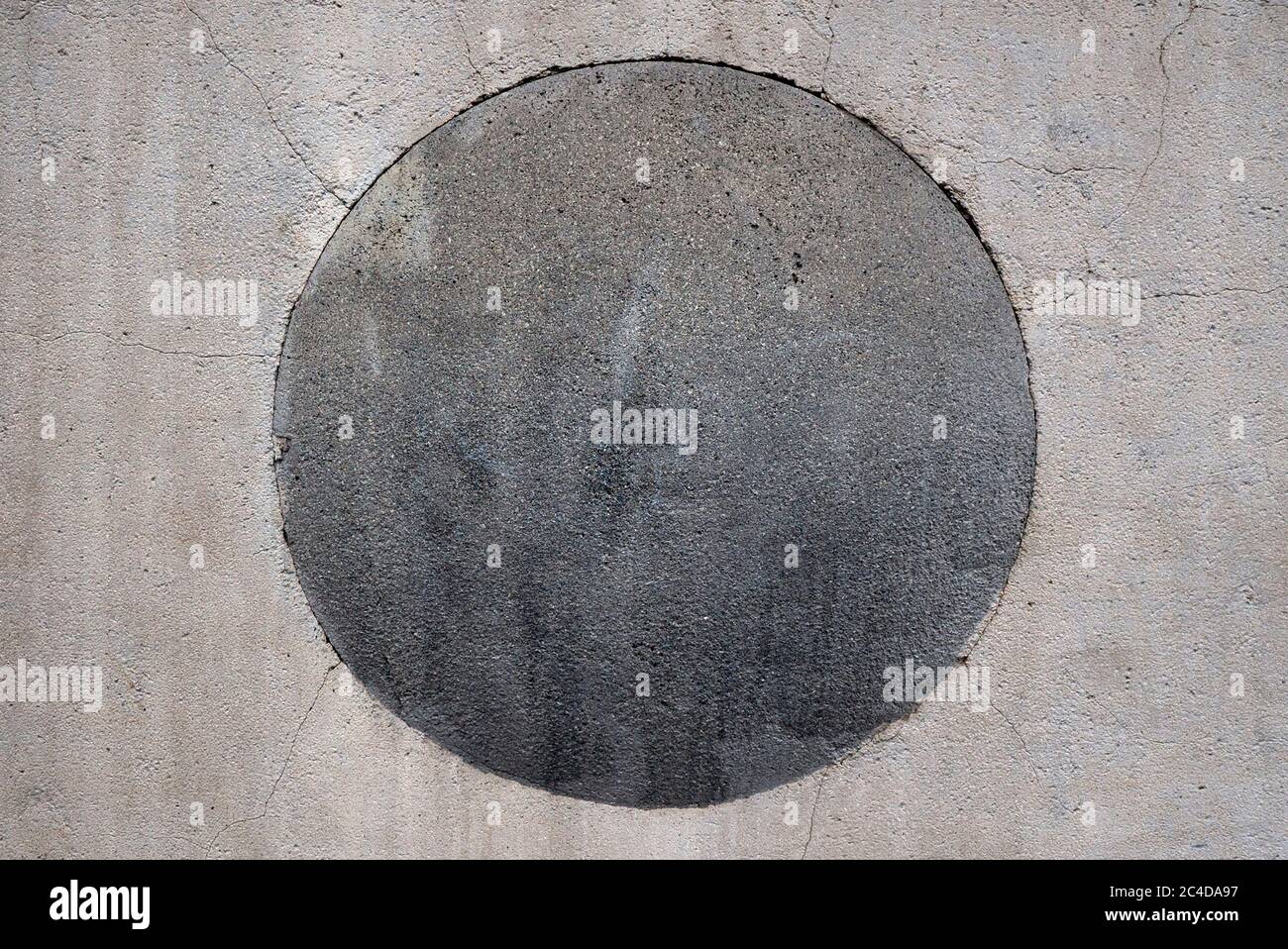 Un primo piano di UN cerchio di cemento grigio all'interno DI UN Parete color crema Foto Stock