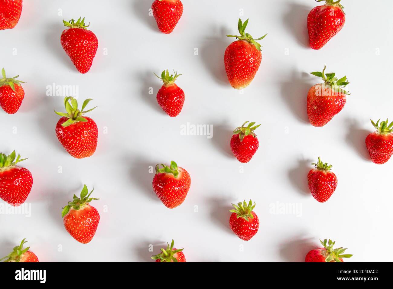 Fragole biologiche deliziose motivo senza cuciture su sfondo grigio, vista dall'alto, piatto. Composizione estiva, stile minimal Foto Stock