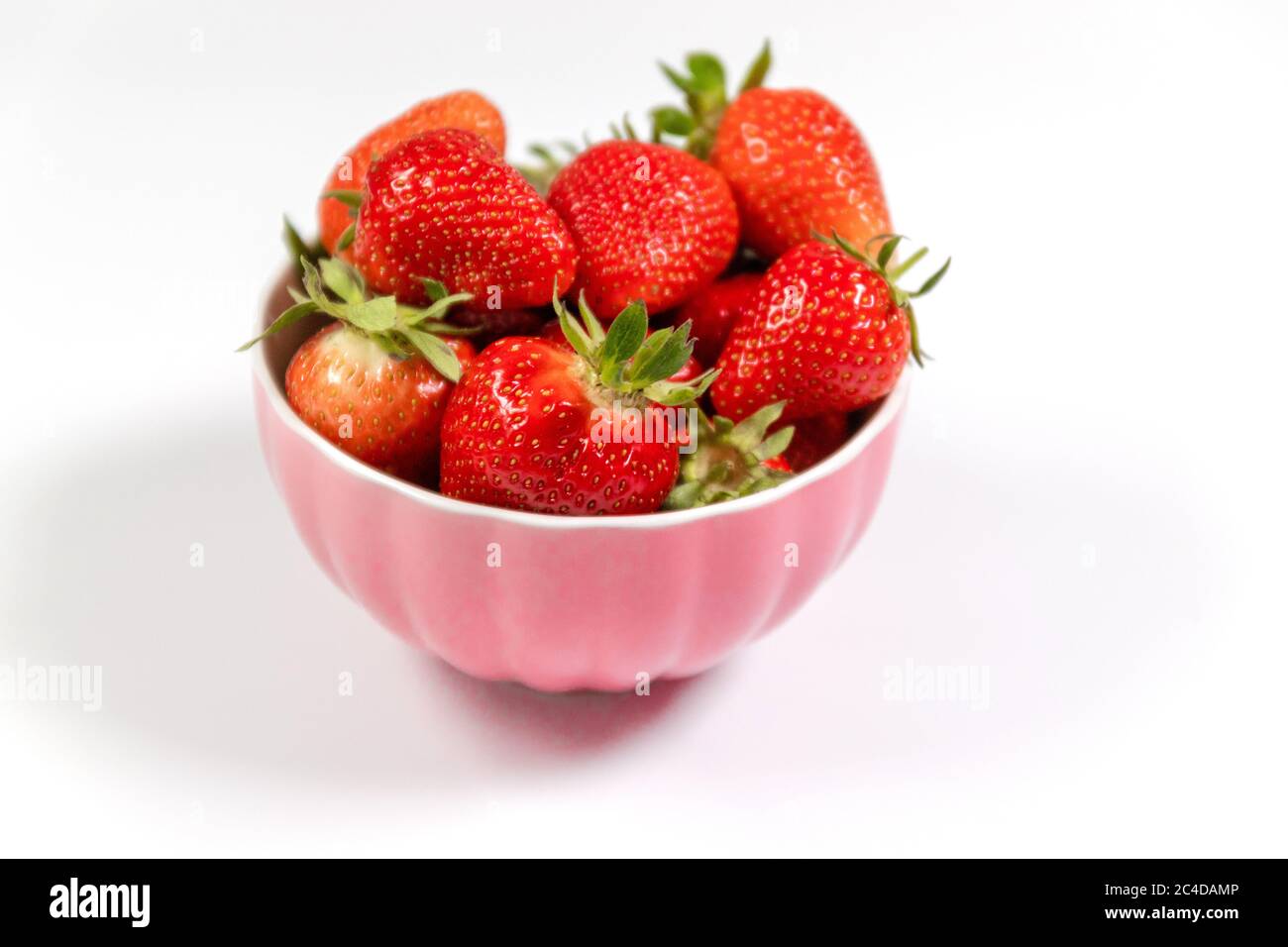 Ciotola con fragole fresche su sfondo bianco. Composizione estiva Foto Stock