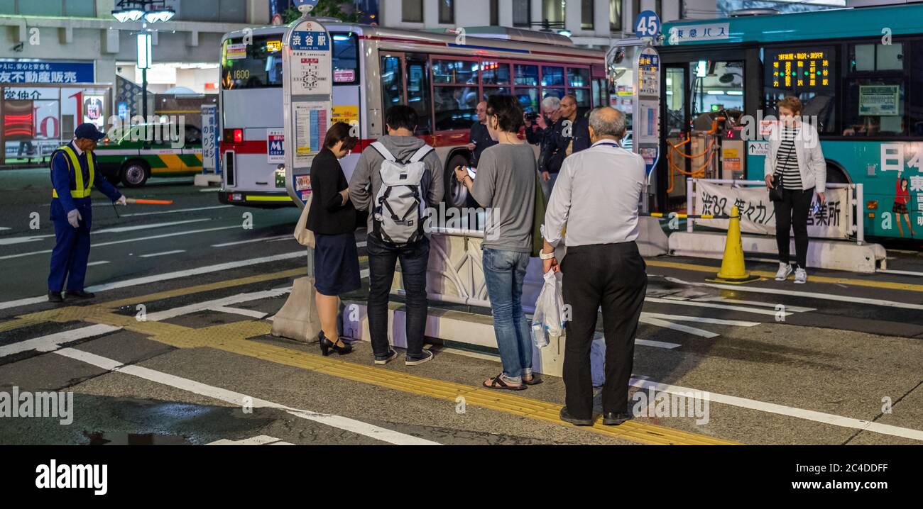 Pendolari in attesa di un autobus alla stazione Shibuya, Tokyo, Giappone di notte. Foto Stock