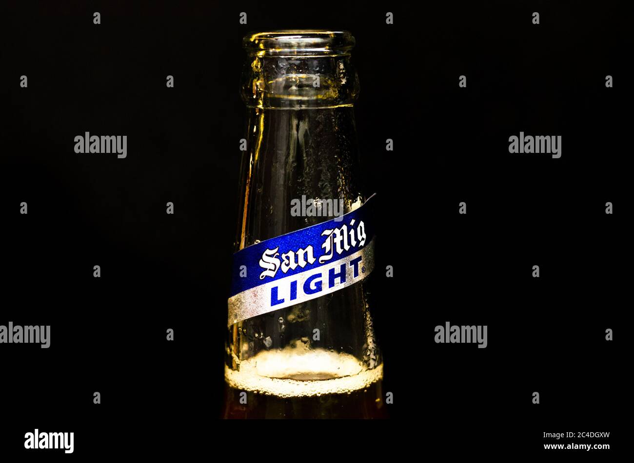 Primo piano vista della bocca della bottiglia di birra San Miguel Light con etichetta argento e blu su sfondo di marmo nero Foto Stock