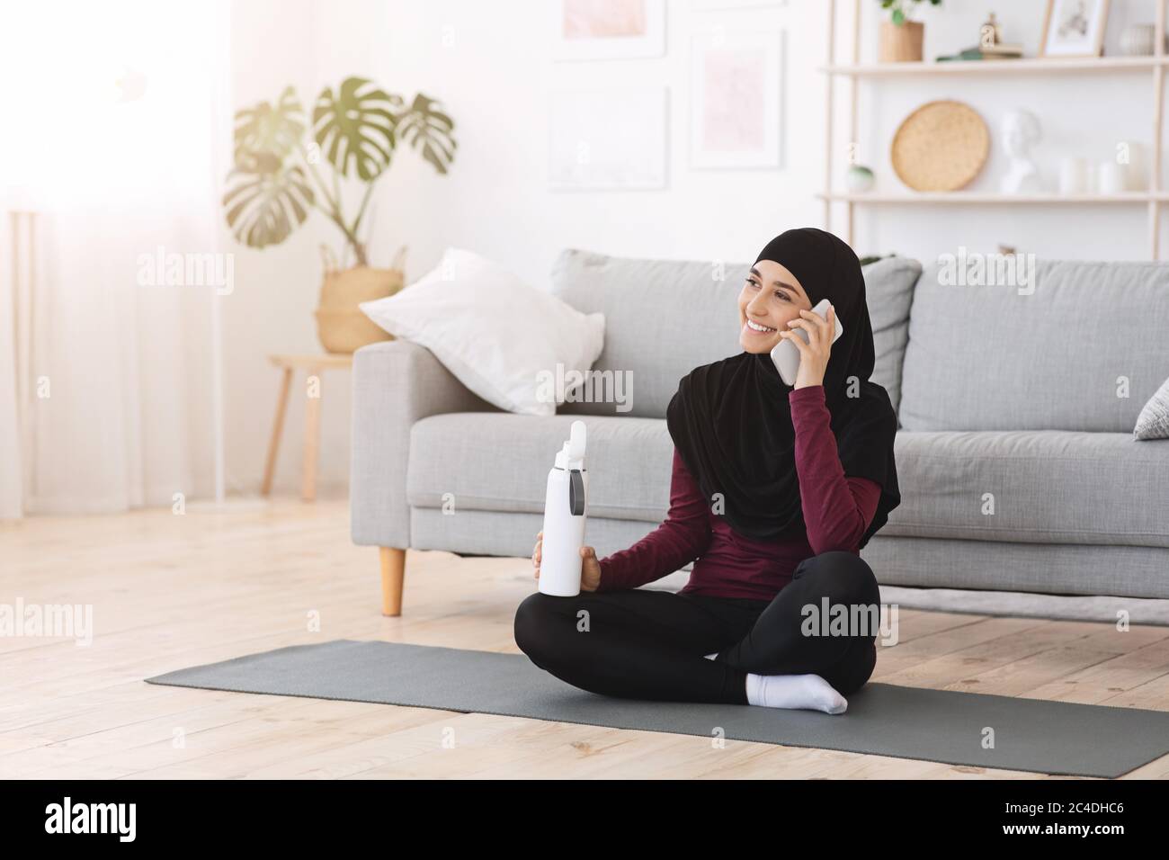 Ragazza musulmana felice che parla su cellulare dopo l'addestramento di idoneità a casa Foto Stock