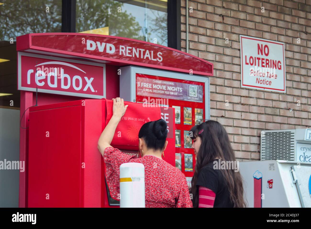 MIDDLETOWN, NY, STATI UNITI - 02 maggio 2020: Middletown, NY 05/02/2020: Due donne che usano il chiosco della macchina del noleggio di DVD di RedBox fuori delle fattorie di Cumberland Foto Stock