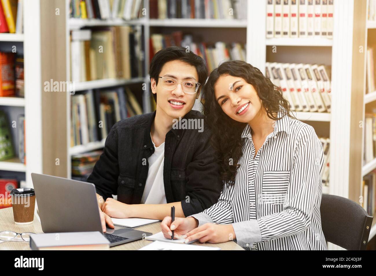 Sorridente studenti multietnici che imparano nella biblioteca moderna Foto Stock