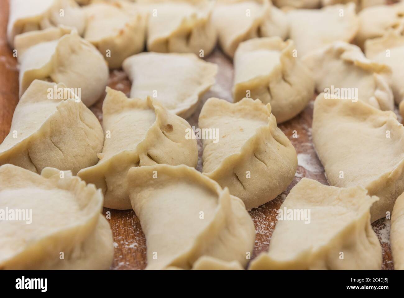 Gnocchi cinesi crudi, non cotti in casa su un piatto di legno Foto Stock