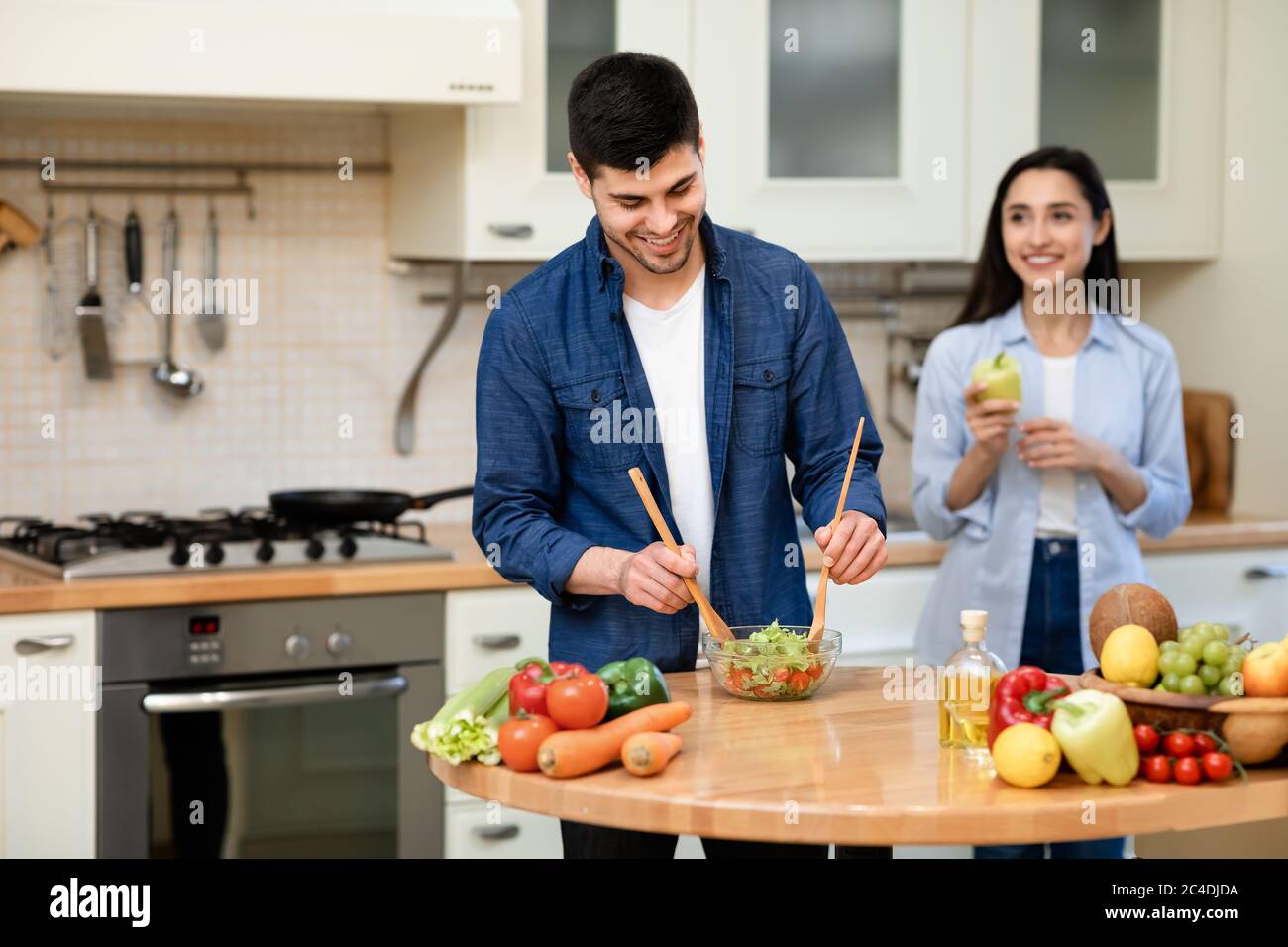 Felice coppia che prepara insieme l'insalata nella loro casa accogliente Foto Stock