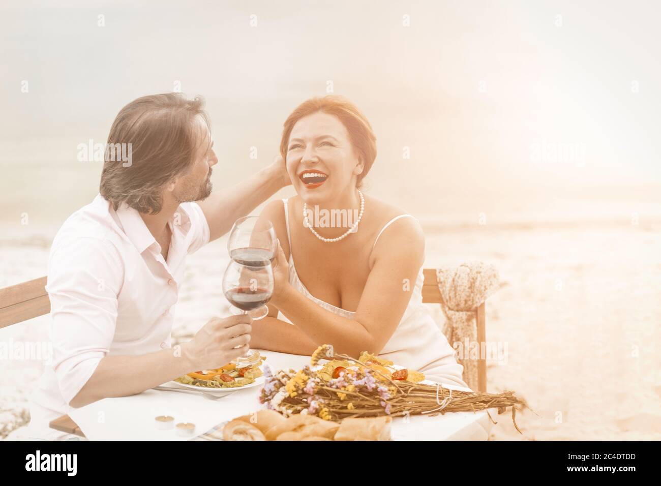 Felice uomo maturo e donna ride bere vino all'aperto. Una coppia innamorata riposa insieme al Coast cafe. Immagine colorata Foto Stock