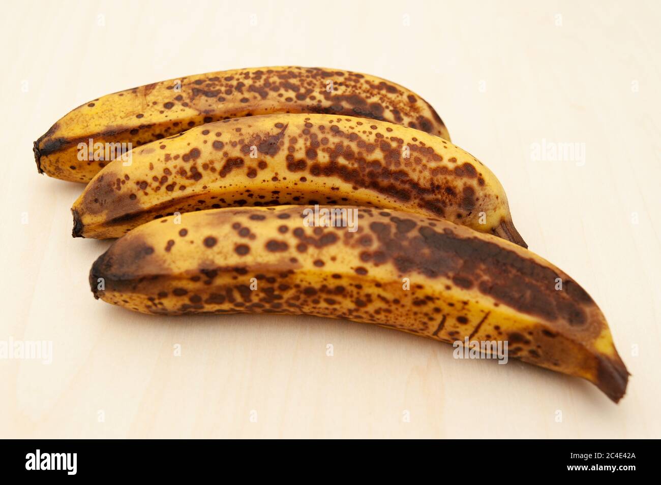 Tre banane mature isolate su sfondo di legno chiaro. Vista dall'alto. Spazio di copia. Foto Stock