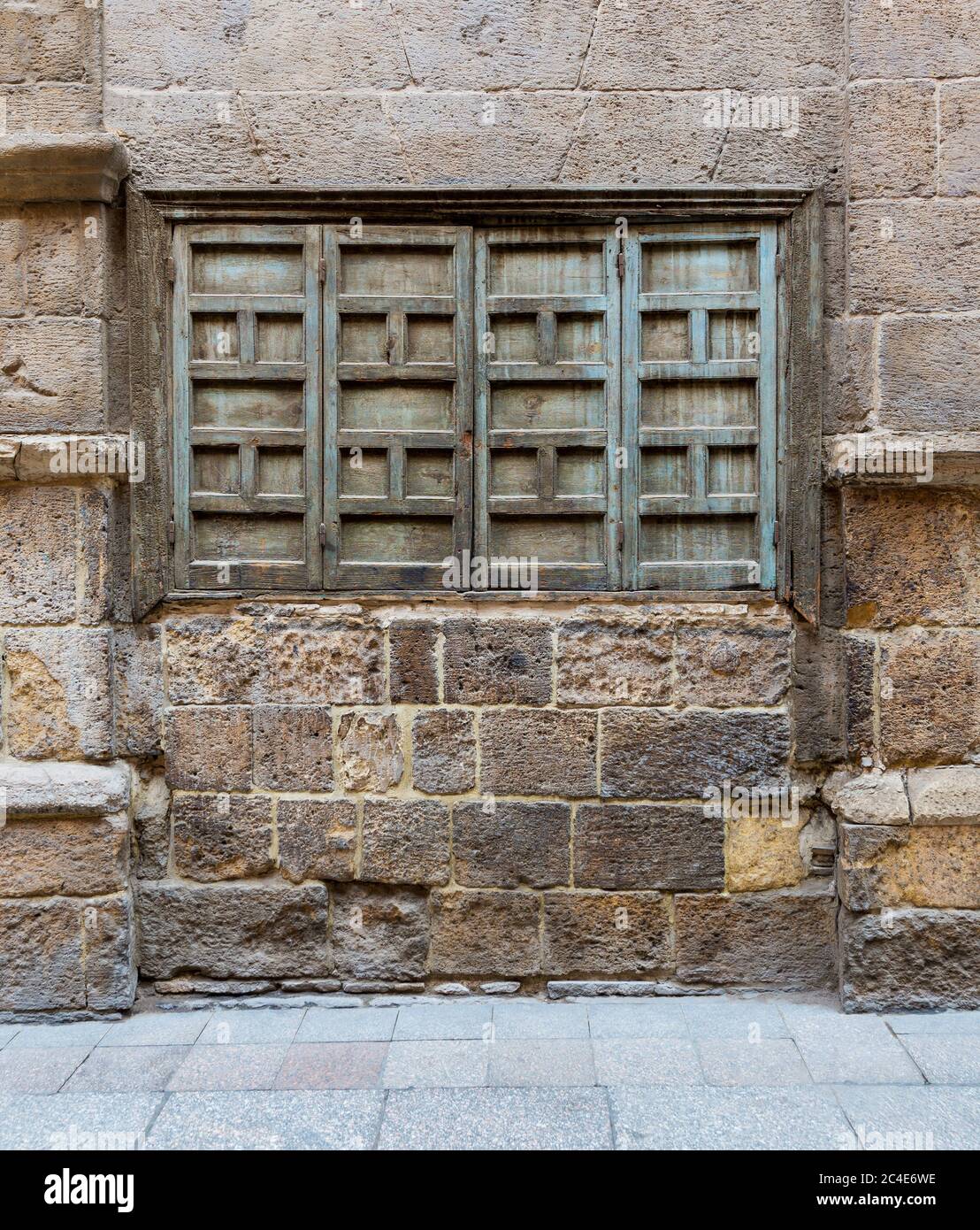 Esterno di pietra intemperie muro di mattoni e verde grunge chiuso finestra a cassettoni sul quartiere abbandonato Foto Stock