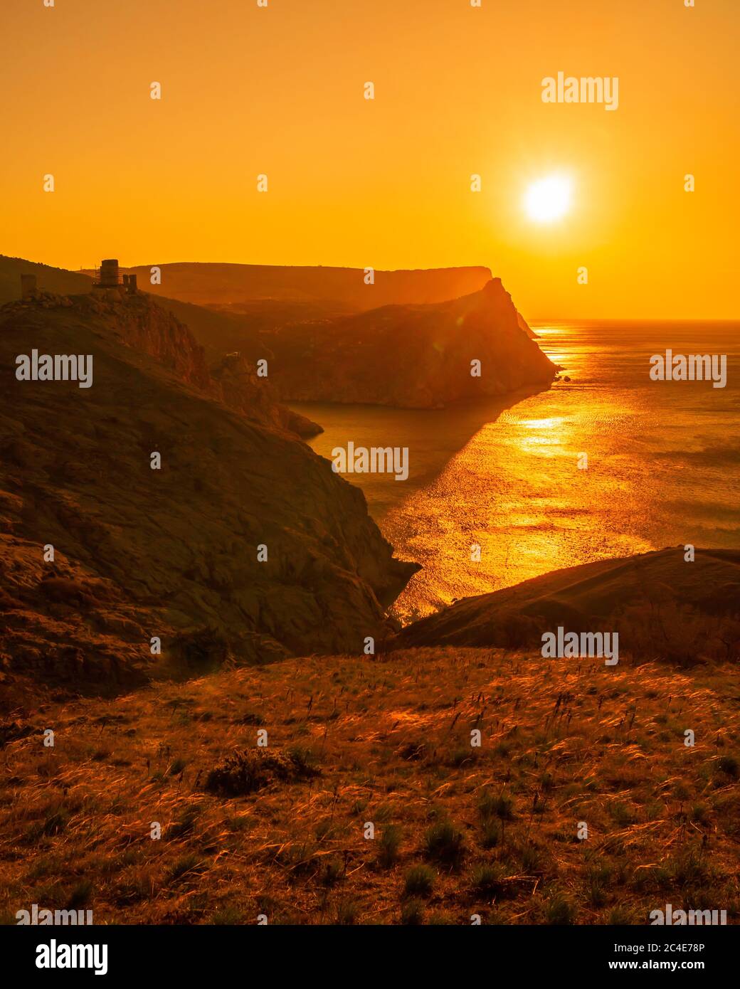 Un tramonto rosso ardente con la sagoma di una scogliera e di un castello sul mare Foto Stock