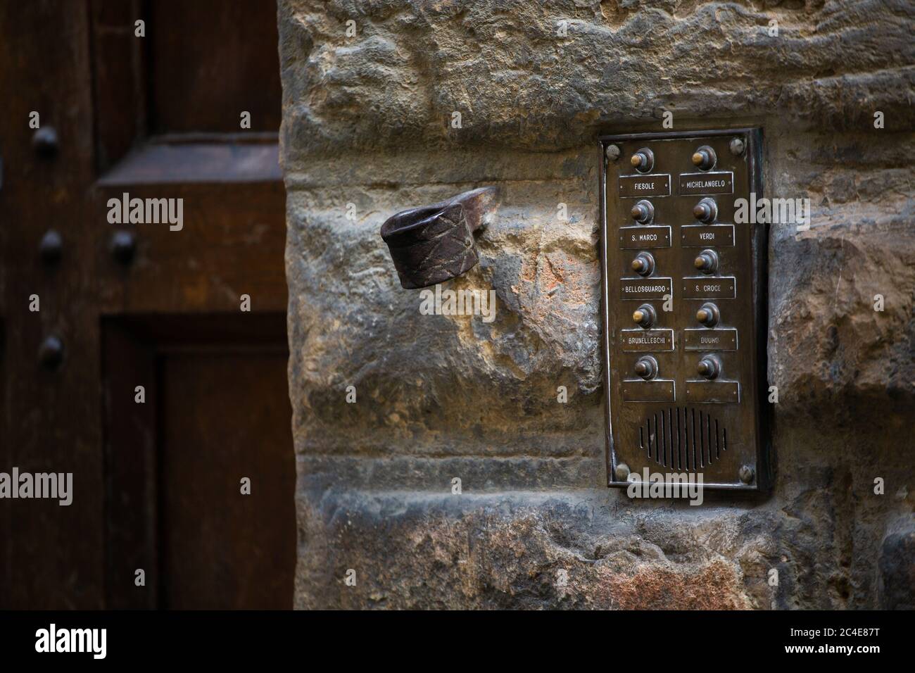 Citofono d'epoca all'ingresso dell'edificio. La vecchia targhetta con i pulsanti sulla piastra in bronzo si trova sulla parete in pietra. Concetto di sicurezza domestica. Maggio 2013. Pisa, Italia Foto Stock